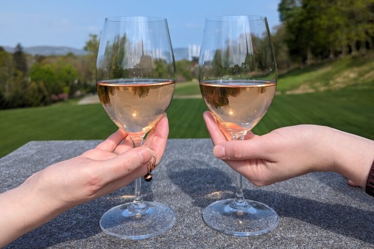 Two hands hold up rose wine glasses outside Photo Credit: Srini Shah
